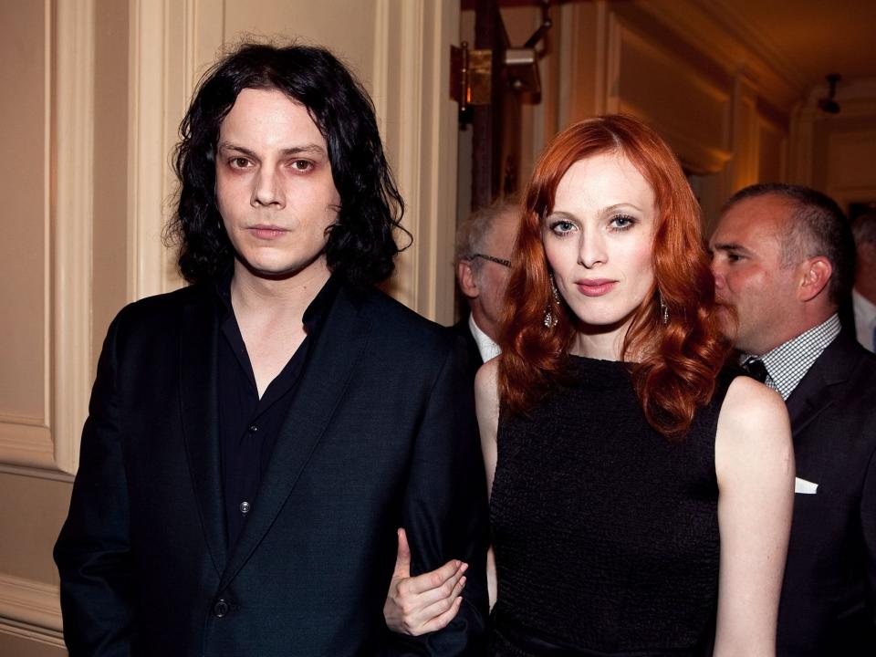 Jack in a black suit and shirt and Karen with red hair and a black dress.