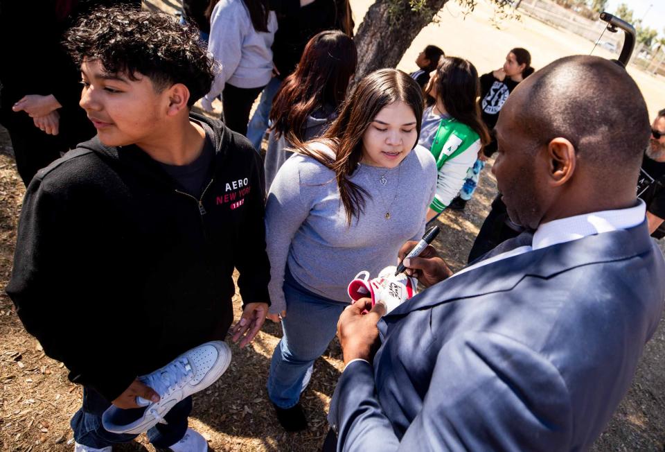 Former NFL player Wesley Leasy autographs a student's sneaker during a visit to Kenilworth School in Phoenix on Feb. 12, 2024.