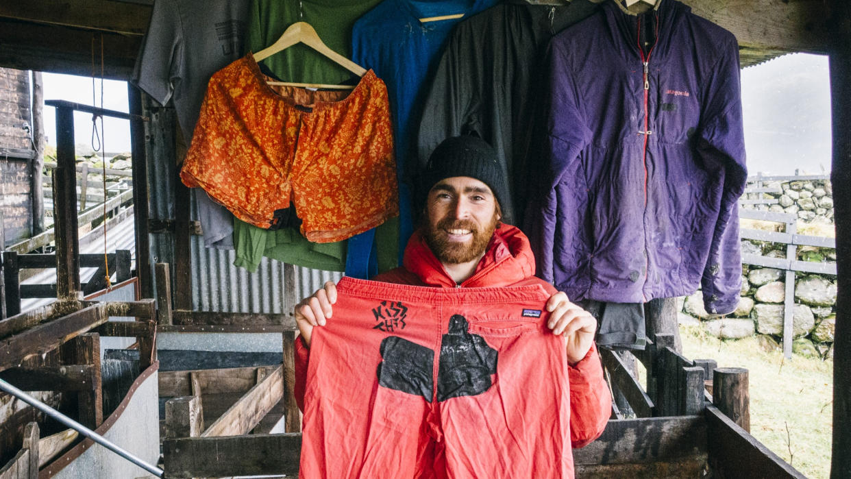  Man holding up repaired Patagonia pants. 