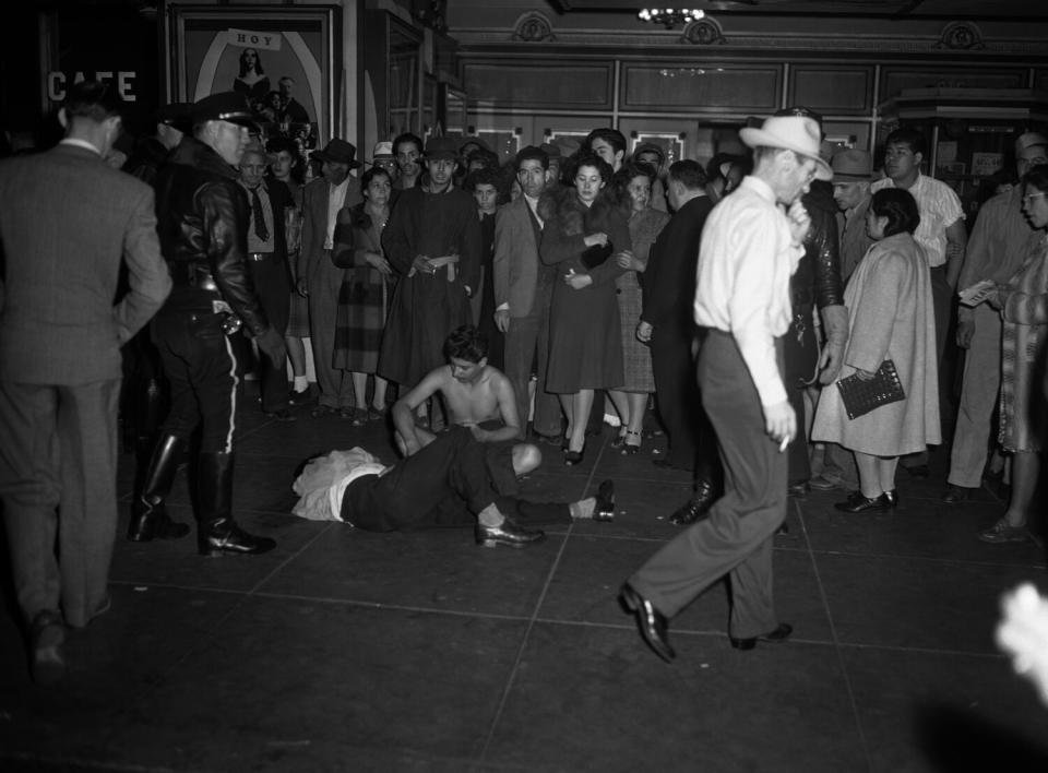 Two youths are on the ground as a crowd gathers around them.