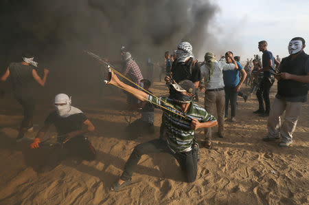 Palestinians hurl stones at Israeli troops during a protest calling for lifting the Israeli blockade on Gaza and demanding the right to return to their homeland, at the Israel-Gaza border fence in the southern Gaza Strip October 5, 2018. REUTERS/Ibraheem Abu Mustafa