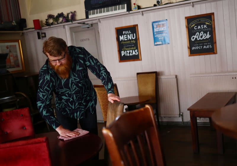 Landlord Are Kolltveit cleans a table in the Chandos Arms pub ahead of pubs reopening following the coronavirus disease (COVID-19) outbreak, in London