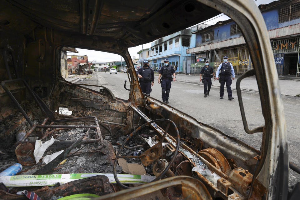 Australian Federal Police inspect burnt out areas of Chinatown in Honiara, Solomon Islands, Tuesday, Nov. 30, 2021. New Zealand announced Wednesday, Dec. 1, 2021, that they will send up to 65 military and police personnel to the Solomon Islands over the coming days after rioting and looting broke out there last week.(Gary Ramage via AP)