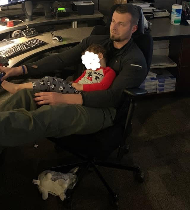 Clinton County Illinois Sheriff's Office Detective McClaren sits with a child asleep on his lap.