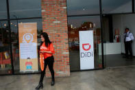 The logo of Chinese ride-hailing firm Didi Chuxing is seen as an employee walks out of the new drivers' center in Toluca, Mexico, April 23, 2018. REUTERS/Carlos Jasso