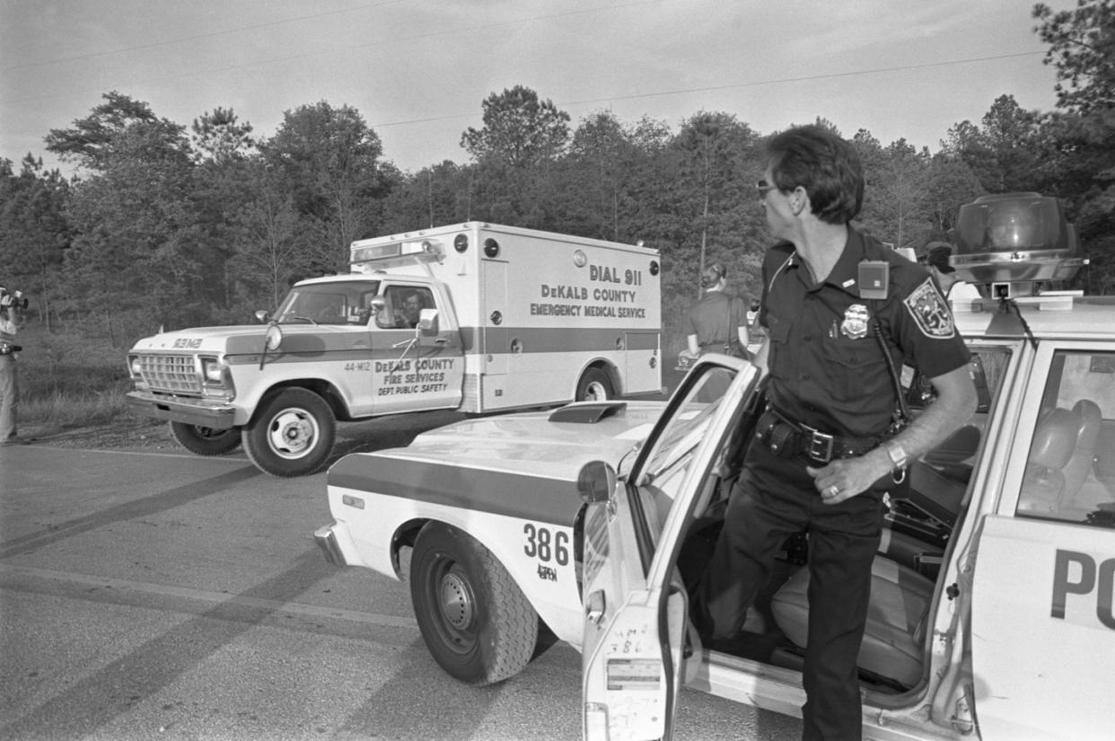 Police officer looks as ambulance carries body of Joseph Bell