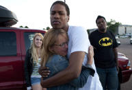 Judy Goos, second from left, hugs her daughters friend, Isaiah Bow, 20, while eye witnesses Emma Goos, 19, left, and Terrell Wallin, 20, right, gather outside Gateway High School where witness were brought for questioning Friday, July 20, 2012 in Denver. A gunman wearing a gas mask set off an unknown gas and fired into a crowded movie theater at a midnight opening of the Batman movie "The Dark Knight Rises," killing at least 12 people and injuring at least 50 others, authorities said. (AP Photo/Barry Gutierrez)