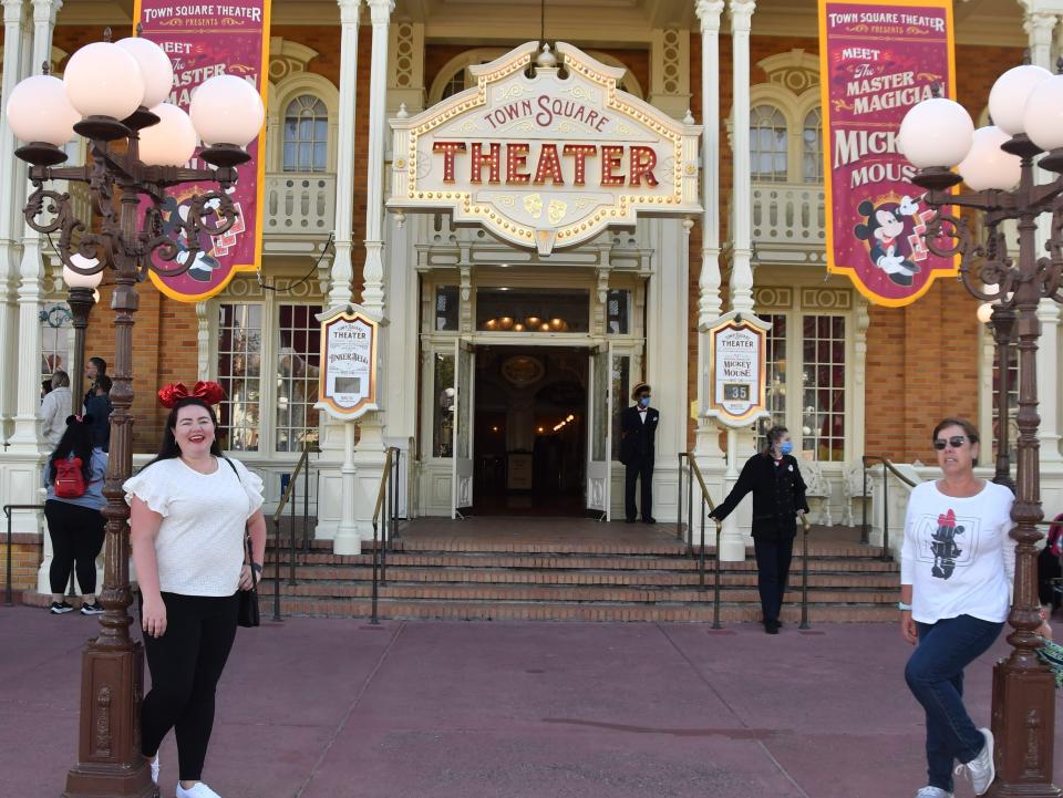 megan and her mom posing in front of the main street theater at disney world