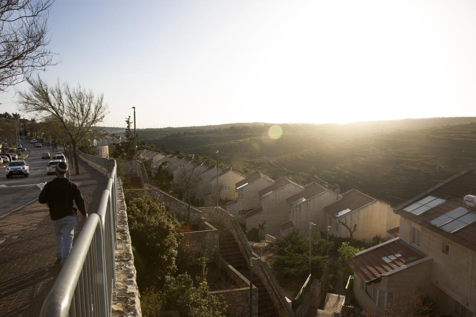 A man walks along a main road in the West Bank Jewish settlement of Efrat, Tuesday, March 16, 2021. Israel went on an aggressive settlement spree during the Trump era, according to an AP investigation, pushing deeper into the occupied West Bank than ever before and putting the Biden administration into a bind as it seeks to revive Mideast peace efforts. (AP Photo/Maya Alleruzzo)