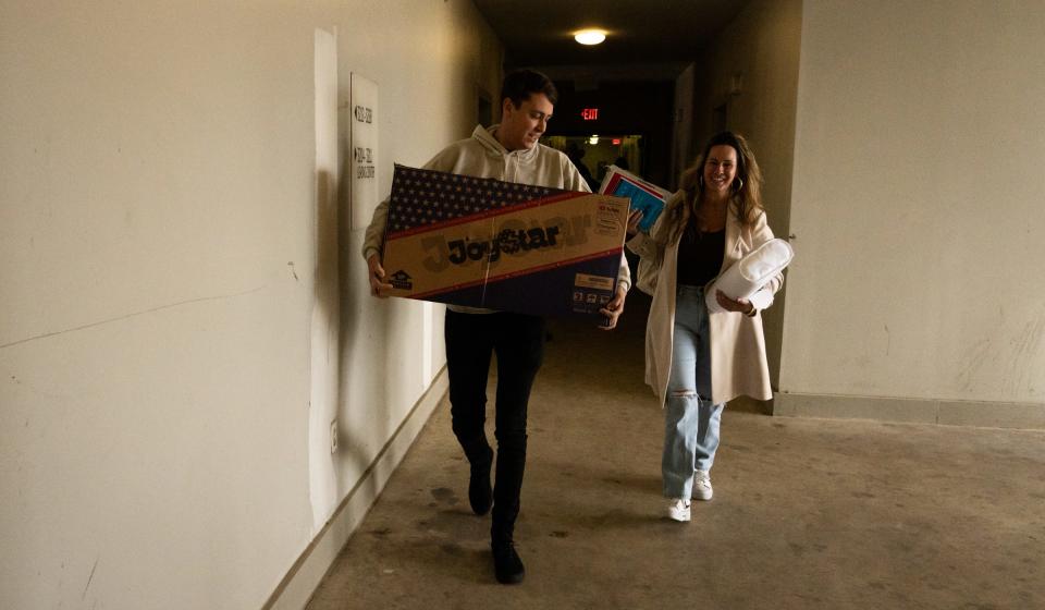 Kyle Breazeale and Caroline Riley from Ownwell carry gifts up to the apartment of Aaliyah Gaulmon and her 4-year-old daughter, Kourtni Chambers.