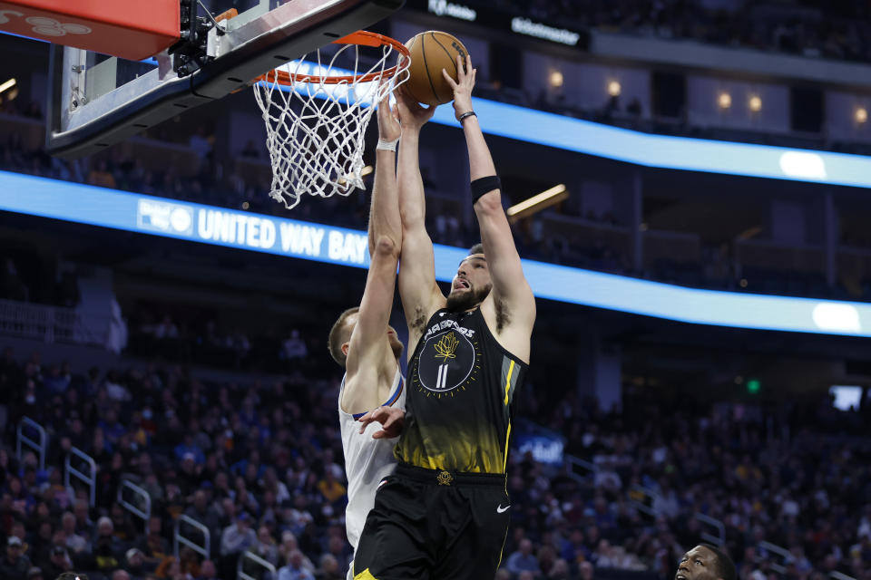 Golden State Warriors guard Klay Thompson (11) shoots over Washington Wizards center Kristaps Porzingis, left, during the first half of an NBA basketball game in San Francisco, Monday, Feb. 13, 2023. (AP Photo/Jed Jacobsohn)