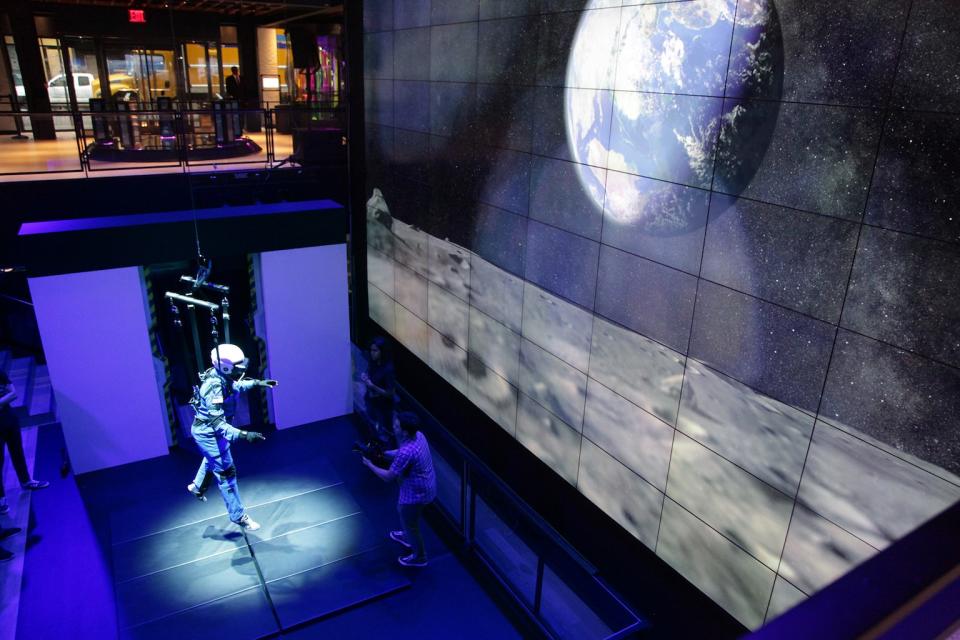 Hanging from a "gravity offload rig" at the Samsung 837 center in New York City, NASA astronaut Mike Massimino takes a virtual trip to the moon on July 17, 2018. <cite>Samsung</cite>