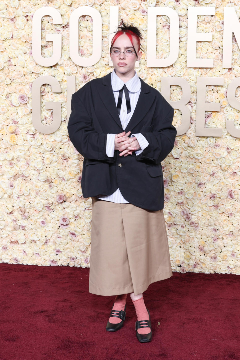 Billie Eilish wears a casual-inspired look by Willy Chavarria and pink socks at the 2024 Golden Globes. 
