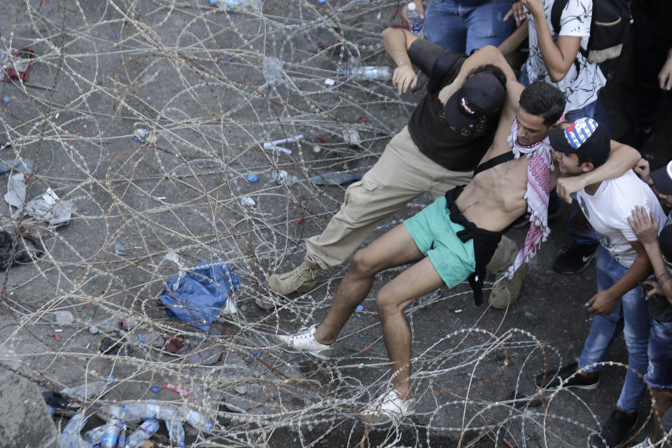 Anti-government protesters try to remove a barbed-wire barrier to advance towards the government building during a protest in Beirut, Lebanon, Saturday, Oct. 19, 2019. The blaze of protests was unleashed a day earlier when the government announced a slate of new proposed taxes, including a $6 monthly fee for using Whatsapp voice calls. The measures set a spark to long-smoldering anger against top leaders from the president and prime minister to the numerous factional figures many blame for decades of corruption and mismanagement. (AP Photo/Hassan Ammar)