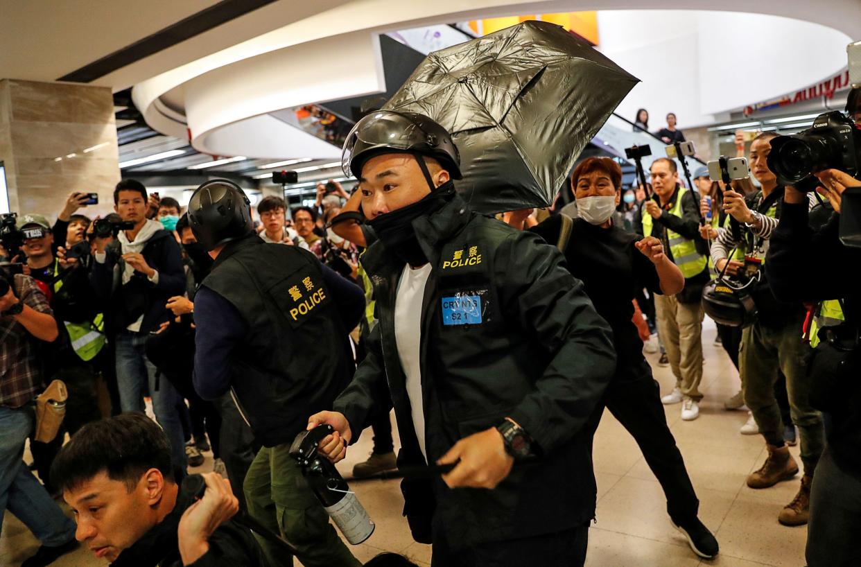 A woman hits a police officer with an umbrella as others detain an anti-government protester during a demonstration inside a mall in Hong Kong, China December 15, 2019. REUTERS/Danish Siddiqui