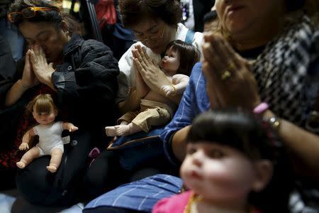 Devotees pay respect to a Buddhist monk as they sit with their "child angel" dolls during a blessing ritual at Wat Bua Khwan temple in Nonthaburi, Thailand, January 26, 2016. REUTERS/Athit Perawongmetha