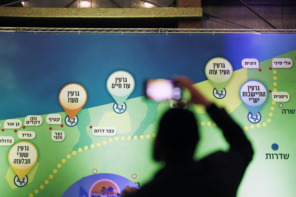An attendee takes a picture near a map suggesting a vision for Israeli settlements in Gaza at the conference in Jerusalem on Sunday. (Kobi Wolf for NBC News)