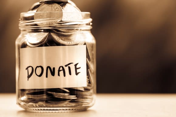 A donation jar with silver coins filled to the brim.