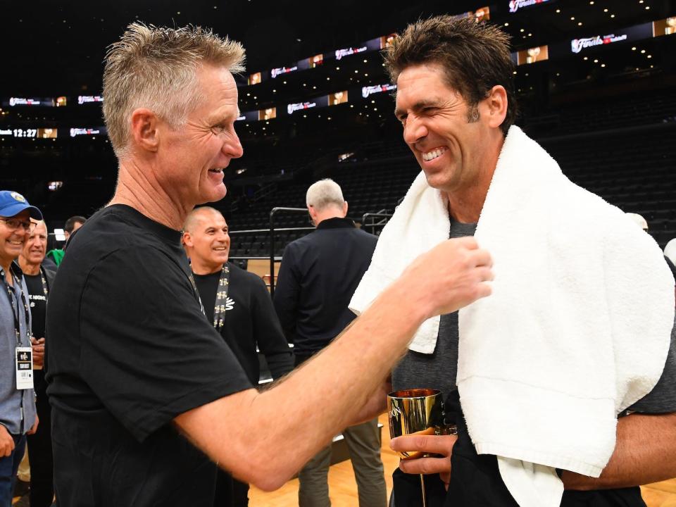Steve Kerr and Bob Myers smile while talking after the Warriors won the 2022 championship.