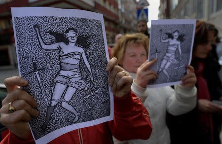 People shout slogans while holding pictures during a protest outside the courts of Aviles, after a Spanish court sentenced five men accused of the group rape of an 18-year-old woman at the 2016 San Fermin bull-running festival each to nine years in prison for the lesser charge of sexual abuse, in Spain, April 27, 2018. REUTERS/Eloy Alonso