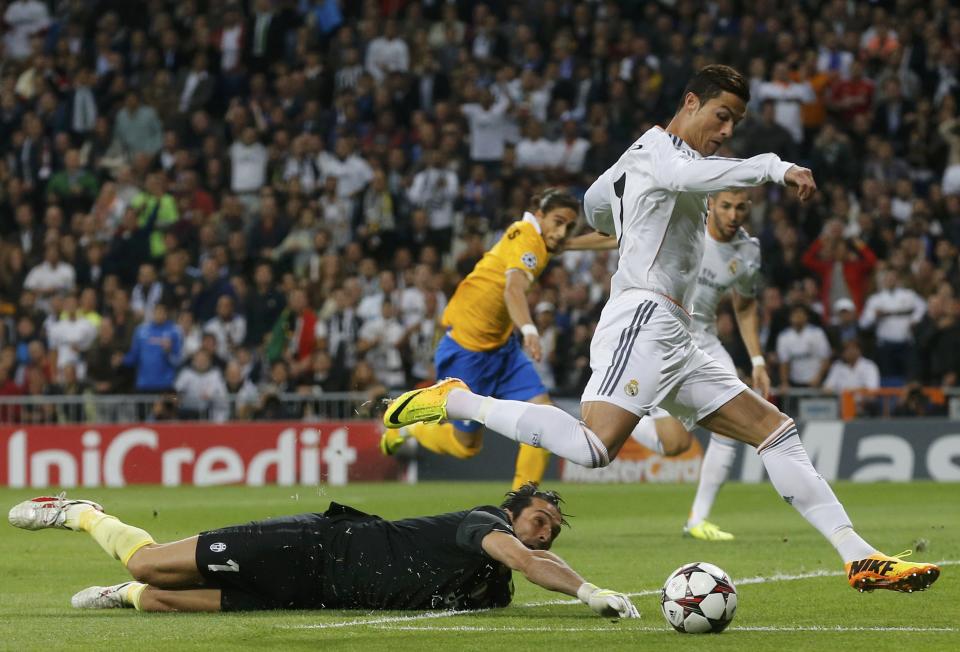 Real Madrid's Cristiano Ronaldo (R) eludes Juventus' goalkeeper Gianluigi Buffon to score a goal during their Champions League soccer match at Santiago Bernabeu stadium in Madrid October 23, 2013. REUTERS/Paul Hanna (SPAIN - Tags: SPORT SOCCER)