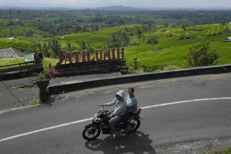 Motorists ride past rice fields fed by a traditional terrace irrigation system called a "subak" in Jatiluwih in Tabanan, Bali, Indonesia, Monday, April 18, 2022. Bali faces a looming water crisis from tourism development, population growth and water mismanagement, experts and environmental groups warn. While water shortages are already affecting the UNESCO site, wells, food production and Balinese culture, experts project these issues will worsen if existing policies are not equally enforced across the entire island. (AP Photo/Tatan Syuflana)