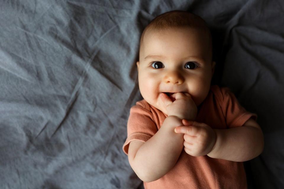 small beautiful child lies on the bed on their stomach and smiles