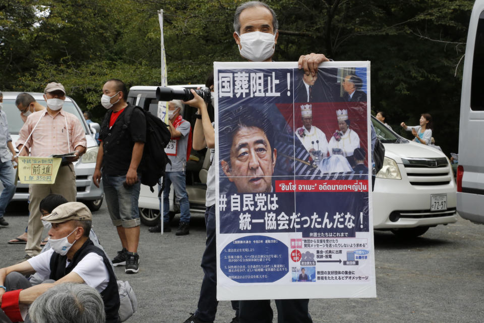 A protester holds a poster showing the image of former Prime Minister Shinzo Abe, at a gathering a park in Tokyo Friday, Sept. 23, 2022, demanding the cancellation of former Japanese Prime Minister Shinzo Abe’s state funeral. (AP Photo/Yuri Kageyama)