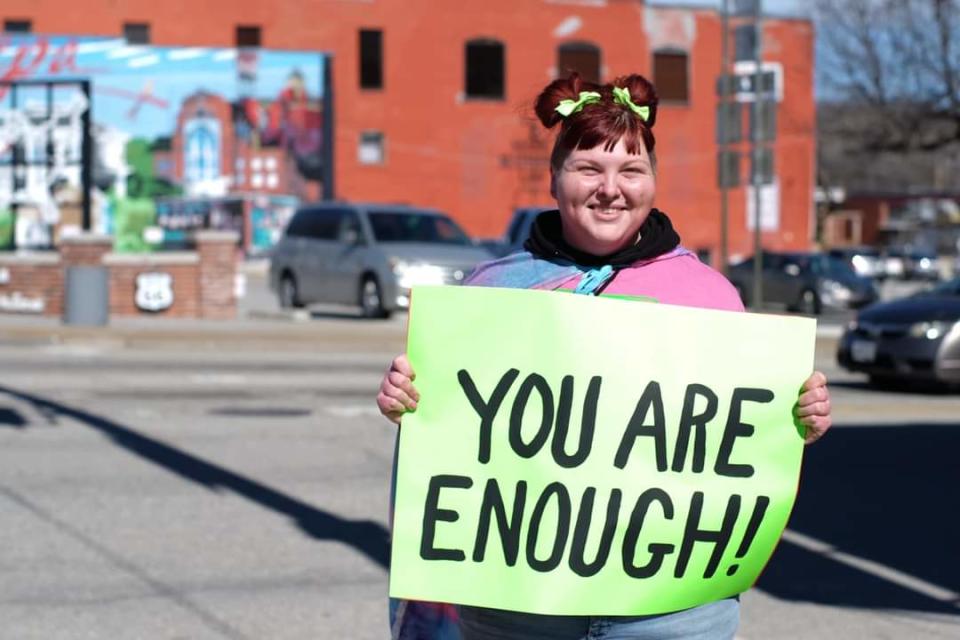 Emily-Sue Snyder, 32, holds a sign at an event for her "Stay Another Day: Suicide Prevention and Awareness" mission in Sapulpa, Oklahoma in February.