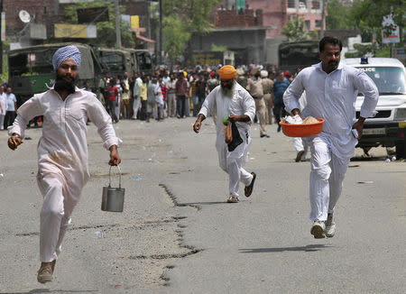 Local residents run near the site of a gunfight at a police station at Dinanagar town in Gurdaspur district of Punjab, India, July 27, 2015. REUTERS/Munish Sharma