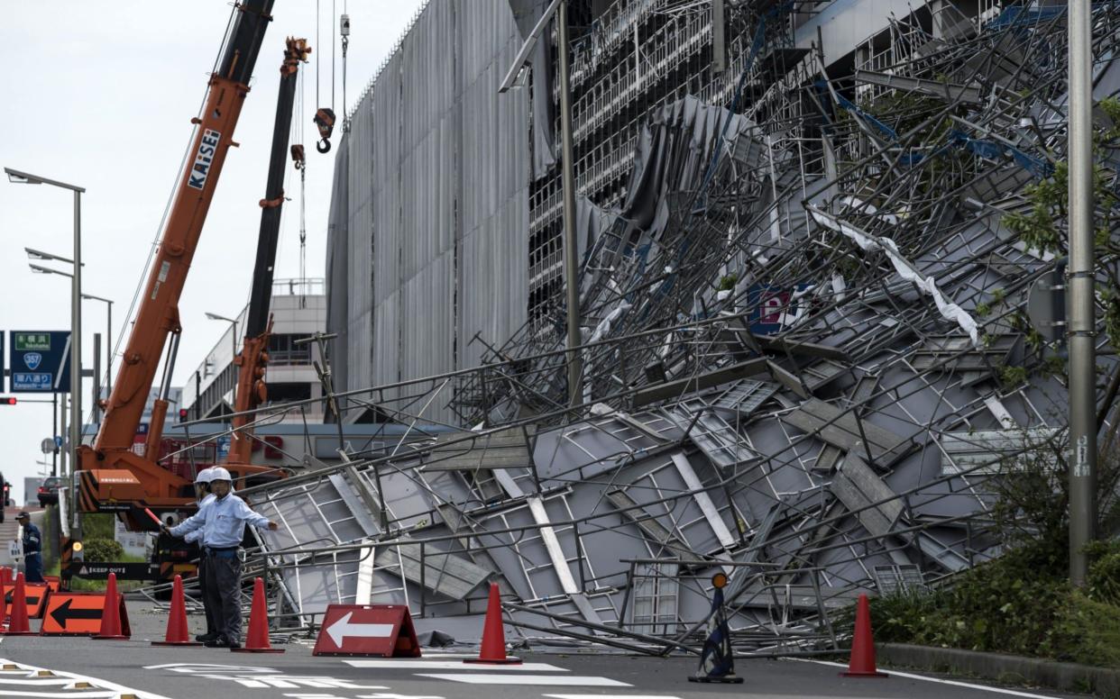 Workers direct traffic in front of damaged scaffolding at the construction site of a parking garage at Haneda Airport - Getty Images AsiaPac