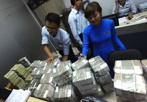 Employees of a local Asia Commercial Bank (ACB) outlet arrange bricks of dong bank notes sent in from the state bank in Hanoi on August 23, 2012. Vietnam's stock markets have lost nearly $4.0 billion in value after two top bankers were arrested this week in a widening police probe into the banking sector, state media said Friday