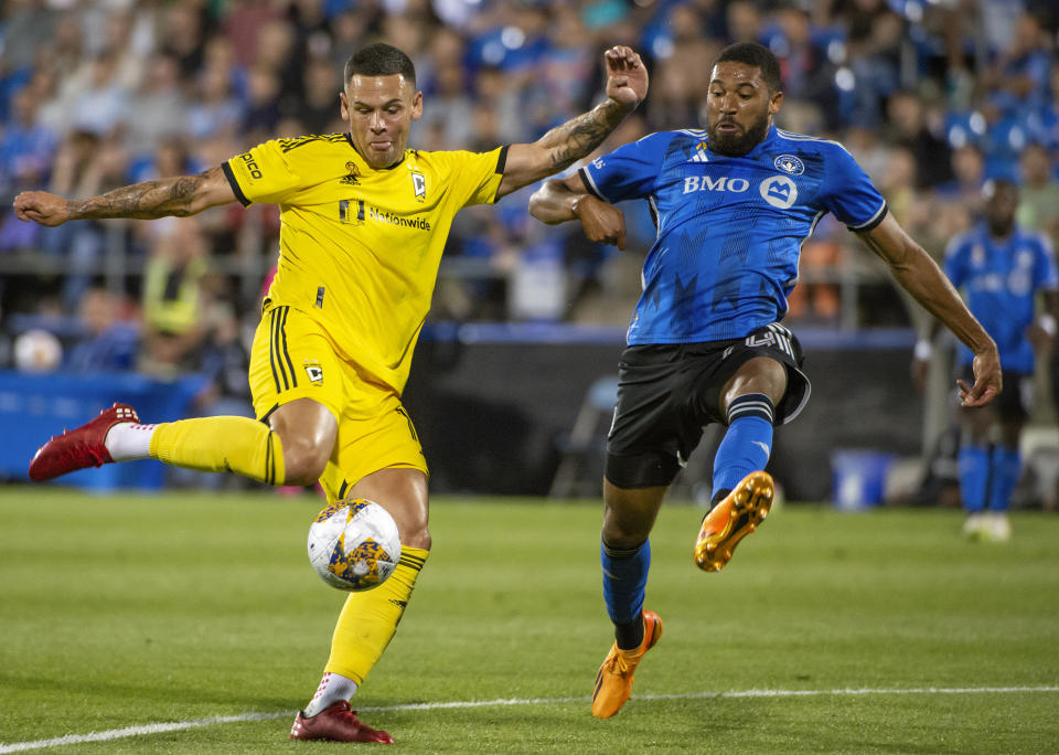 Columbus Crew's Christian Ramirez kicks the ball as CF Montreal's George Campbell defends during the first half of an MLS soccer match Saturday, Sept. 2, 2023, in Montreal. (Peter McCabe/The Canadian Press via AP)