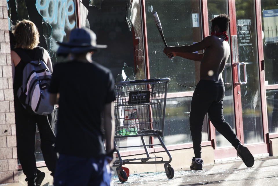 FILE - In this May 28, 2020 file photo, a protestor breaks a window of a business with a baseball bat, in St. Paul, Minn. The destruction caused by vandals and looters in cities across the country, who struck as demonstrators took to the streets in reaction to the killing of George Floyd in Minneapolis, has devastated small businesses already reeling from the coronavirus outbreak. (AP Photo/John Minchillo, File)