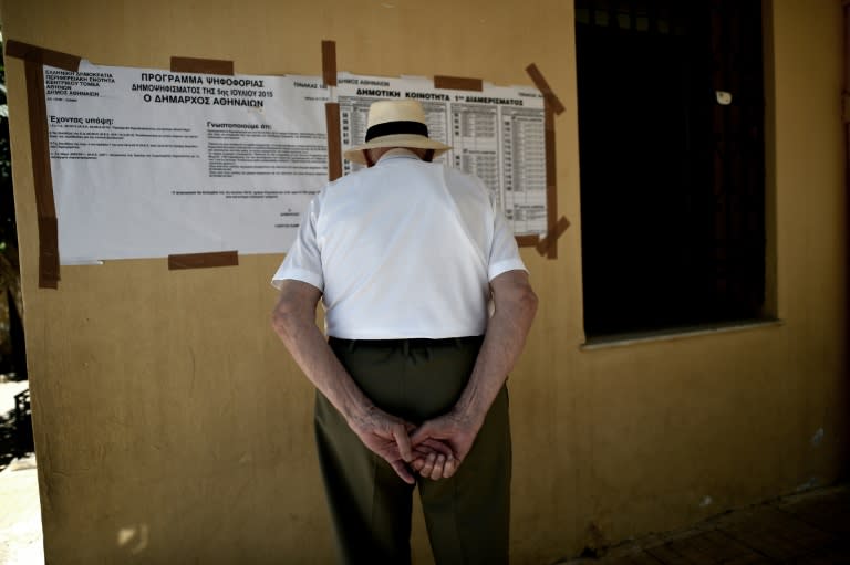 A man reads voting information outside a polling station during the Greek referendum on austerity measures in Athens on July 5, 2015