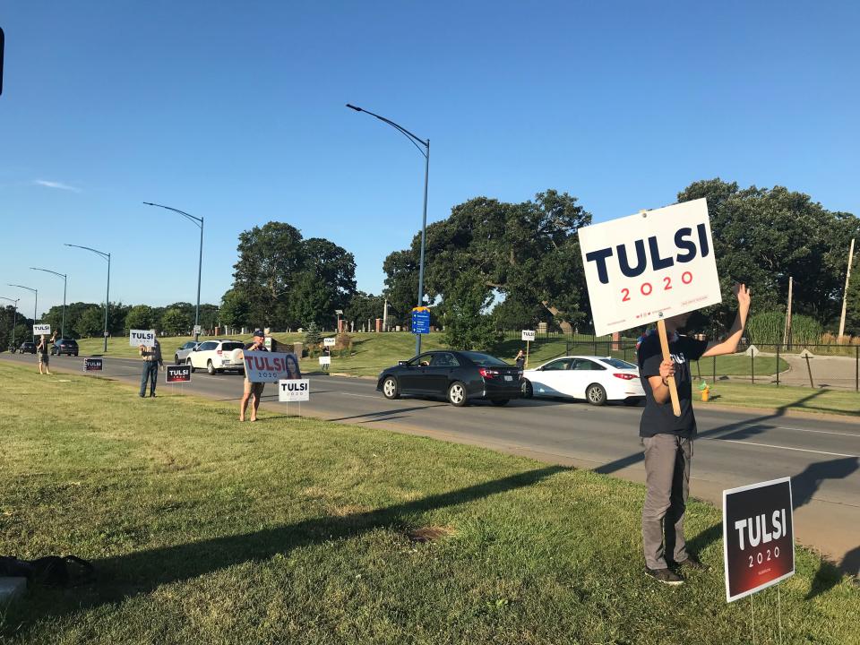 Chris Dec and six other volunteers wave to cars headed towards downtown Des Moines on Martin Luther King Jr. Parkway August 2, 2019.