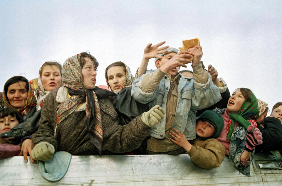 FILE- In this March 29, 1993, file photo, refugees evacuated from the besieged Muslim enclave of Srebrenica, struggle for bread on their arrival in Tuzla, Bosnia. Survivors of the genocide in the eastern Bosnian town of Srebrenica, mainly women, will on Saturday July 11, 2020, commemorate the 25th anniversary of the slaughter of their fathers and brothers, husbands and sons. At least 8,000 mostly Muslim men and boys were chased through woods in and around Srebrenica by Serb troops in what is considered the worst carnage of civilians in Europe since World War II. The slaughter was also the only atrocity of the brutal war that has been confirmed an act of genocide.(AP Photo/Michel Euler, File)