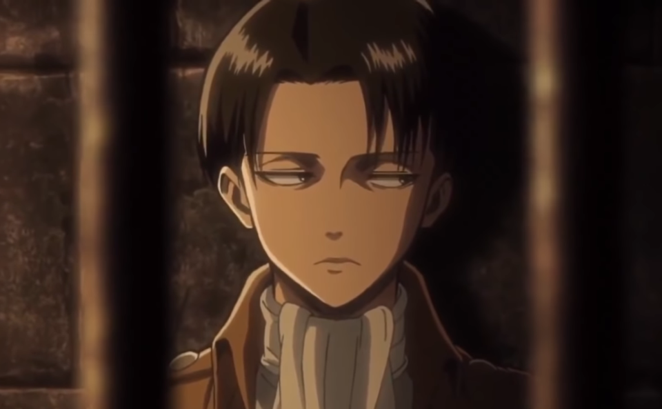 Levi Ackerman staring to the side with bars in front of him in "Attack on Titan"