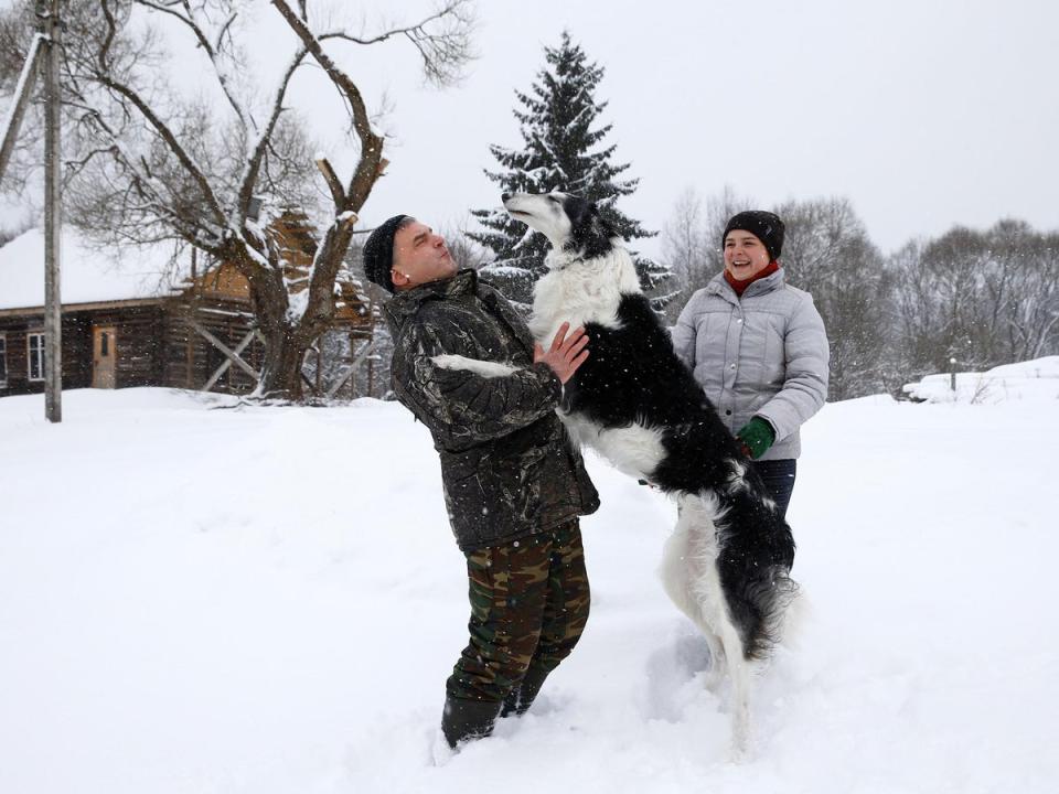 Dmitry Shamovich and his wife Anastasia Kuzmenkova play with the dog Amur at their homestead Zaimka Leshego in the village of Sosnovy Bor, Belarus, February 7, 2018. 