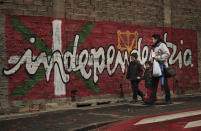 FILE - In this Jan. 12, 2011 file photo, people walk past a wall with painted words in Basque that reads: "Independence", in the small town of Alsasua, northern Spain. Josu Urrutikoetxea, the last known chief of ETA, the now-extinct Basque separatist militant group, goes on trial Monday Oct. 19, 2020 in Paris for terrorism charges that he deems “absurd” because of his role in ending a conflict that claimed hundreds of lives and terrorized Spain for half a century. (AP Photo/Alvaro Barrientos, File)