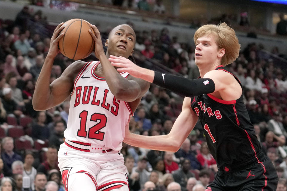 Chicago Bulls' Ayo Dosunmu (12) drives to the basket as Toronto Raptors' Gradey Dick, right, defends during the first half of an NBA basketball game Friday, Oct. 27, 2023, in Chicago. (AP Photo/Charles Rex Arbogast)