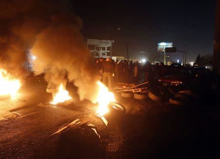 Protesters rallying against layoffs stand near tyres which they burnt, in front of the factory of U.S. automotive supplier Lear on the outskirts of Buenos Aires July 30, 2014. REUTERS/Enrique Marcarian