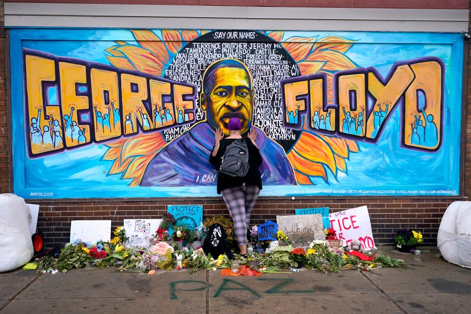 Damarra Atkins pays respect to George Floyd at a mural at George Floyd Square, Friday, April 23, 2021, in Minneapolis.