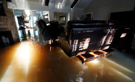 A family puts their belongings on furniture to keep them above floodwaters in their house from Harvey in Houston, Texas August 31, 2017. REUTERS/Rick Wilking