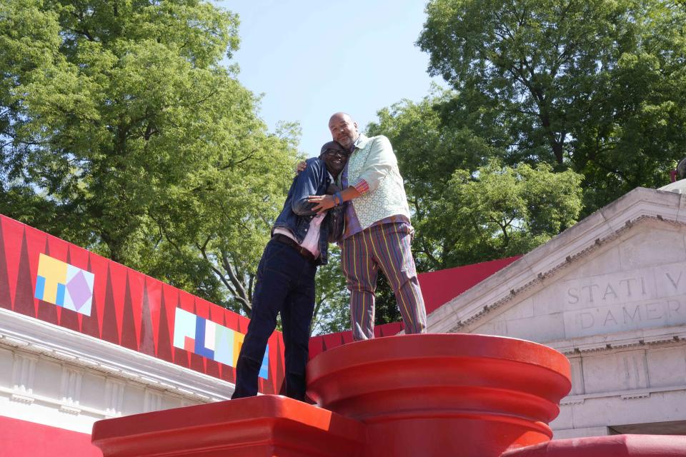 Artist Jeffrey Gibson, right, hugs artist Mark Bradford at the U.S. pavilion during media open day of the 60th Biennale of Arts exhibition in Venice, Italy, Tuesday, April 16, 2024. A Mississippi Choctaw of Cherokee descent, Gibson is the first Native American to represent the United States solo at the Venice Biennale, the world’s oldest contemporary art show. Gibson mixes Western modernism and Native American craft in his vibrantly hued paintings and sculptures. (AP Photo/Luca Bruno)