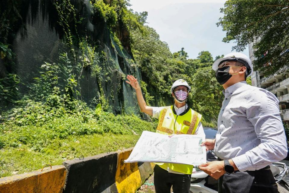 Penang exco Zairil Khir Johari (right) looks at the rockfall netting covering hilly terrain along Lorong Bukit Kukus in Paya Terubong April 25, 2022. — Picture by Sayuti Zainudin