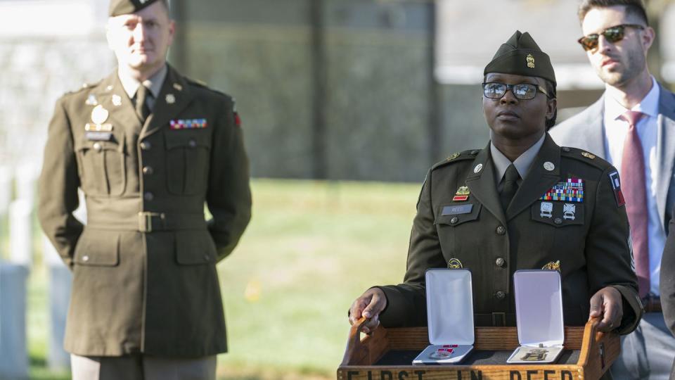 A soldier, right, holds the Bronze Star and Combat Medic Badge to be posthumously presented to Cpl. Waverly B. Woodson Jr. during a ceremony at Arlington National Cemetery on Tuesday, Oct. 11, 2023 in Arlington, Va. (Kevin Wolf/AP)