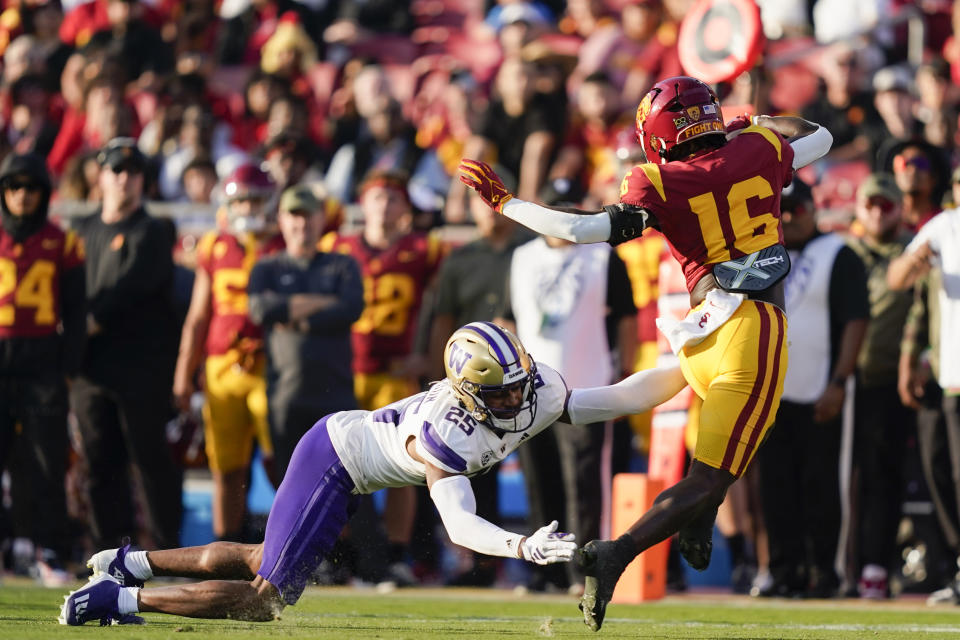 Southern California wide receiver Tahj Washington, right, dodges Washington cornerback Elijah Jackson during the first half of an NCAA college football game Saturday, Nov. 4, 2023, in Los Angeles. (AP Photo/Ryan Sun)