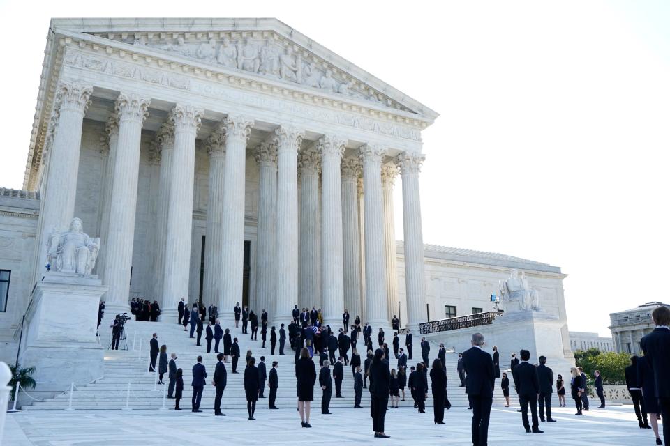 Law clerks and other people gather as the flag-draped casket of late U.S. Supreme Court Justice Ruth Bader Ginsburg arrives at the U.S. Supreme Court in Washington, D.C., September 23, 2020.  / Credit: ALEX BRANDON/POOL/AFP via Getty Images