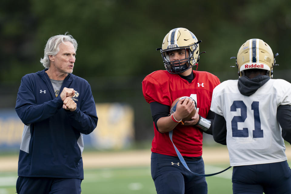 Gallaudet football assistant coach Bob Miller, left, talks with quarterback Gabe Segovia, center, and running back Joshua Kelley, right, using American Sign Language during football practice at Hotchkiss Field, Tuesday, Oct. 10, 2023, in Washington. (AP Photo/Stephanie Scarbrough)